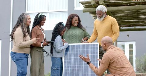 Multigenerational black family learning solar technology while installing home photovoltaic panel