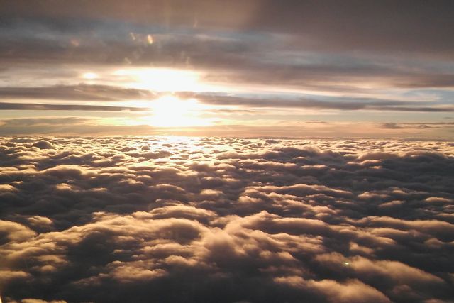Aerial perspective of a dramatic sunset above a sea of clouds, perfect for travel, nature, or aviation-themed content. Ideal for use in websites, travel blogs, and inspirational or calming images.