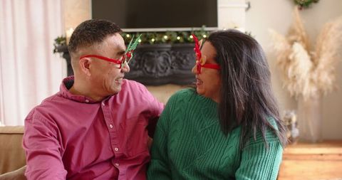 Festive Couple Sharing Laughter with Reindeer Glasses