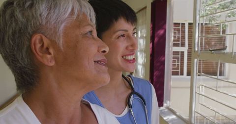 Senior Woman with Caring Doctor Looking Out Window at Retirement Home