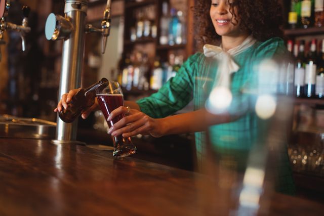 Waitress pouring beer into a pilsner glass at a pub counter, showcasing a lively and welcoming atmosphere. Ideal for use in hospitality industry promotions, bar and pub advertisements, and articles about nightlife or beverage service.