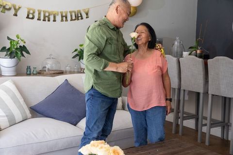 Senior asian couple sharing rose during intimate birthday celebration at home