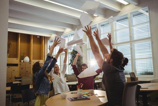 Group of excited business executives throwing paper and having fun in office