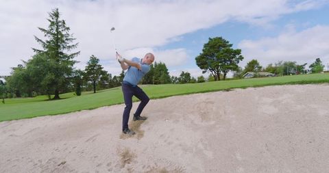 Man Hitting Golf Ball from Sand Bunker on Sunny Course