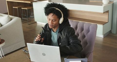 African american podcaster recording from home wearing headphones and leather jacket