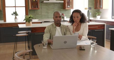 Couple planning finances at home using laptop
