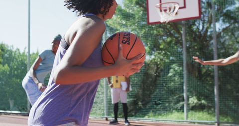 Teen girls training basketball with male coach outdoor sunny day