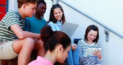 Diverse Teen Group Collaborating with Technology Outdoors