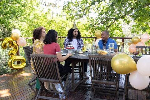 Friends Celebrating Birthday Outdoors with Cake and Balloons