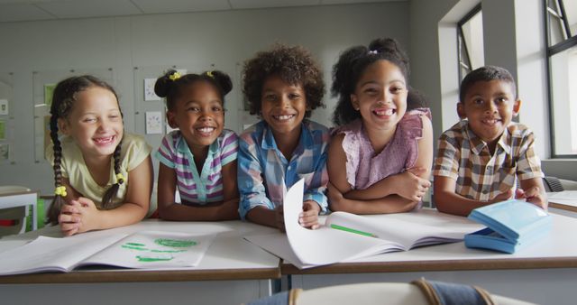 Group of diverse children leaning on table, smiling while studying and bonding in classroom. Great for educational content, school programs, diversity promotion, and childhood friendship concepts.