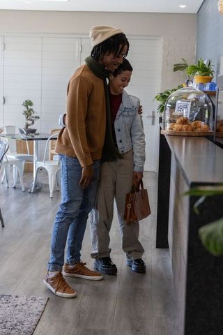 African american couple embracing at cafe counter, smiling while choosing croissants