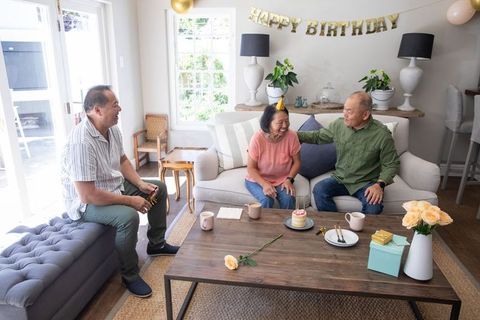 Multigenerational asian family celebrating senior woman birthday in cozy sunlit living room