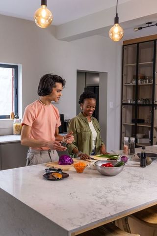 Asian man and african american woman preparing healthy meal on marble kitchen island