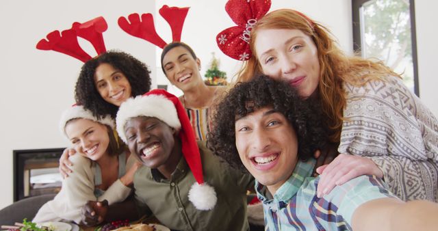 Portrait of happy group of diverse friends looking at camera and smiling. Spending quality time at home together at christmas.