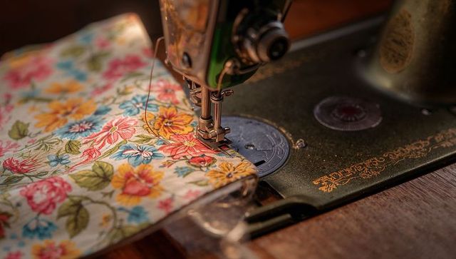 Antique sewing machine stitching colorful floral fabric