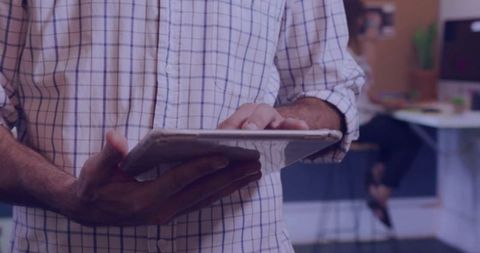 Professional utilizing tablet in open-plan corporate office