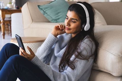 Young Woman Relaxing with Headphones and Smartphone in Cozy Living Room