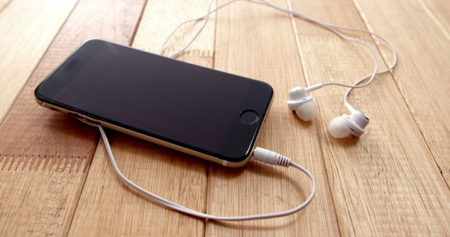 Smartphone with white earbuds placed on a wooden surface. Suitable for illustrating technology usage, portable audio devices, modern gadgets, staying connected, listening to music or podcasts. Ideal for blogs, articles, advertisements, or websites focusing on tech products and lifestyle.