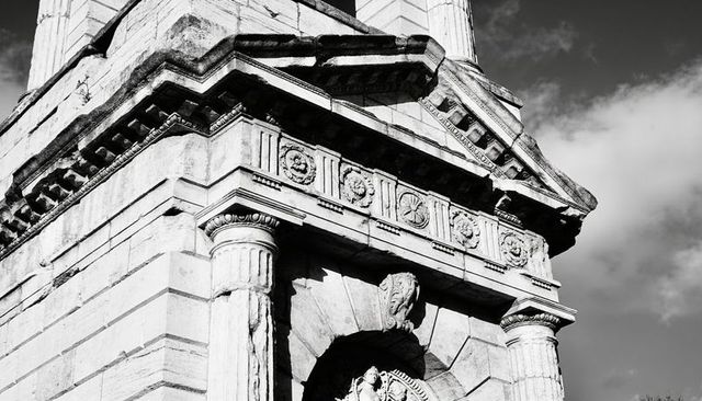 Neoclassical stone facade with fluted columns and ornate pediment in monochrome