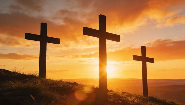 Three wooden crosses on hill at sunrise silhouette with sun halo and warm sky