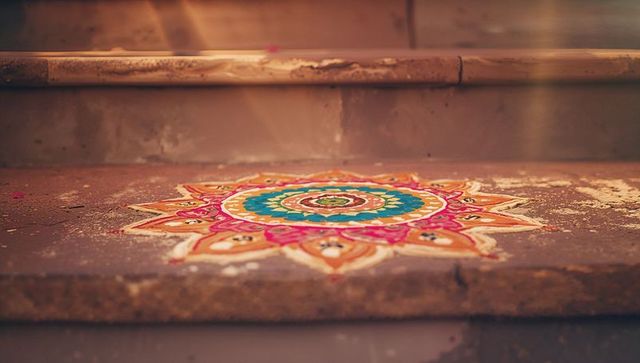 Vibrant rangoli mandala on weathered step entrance