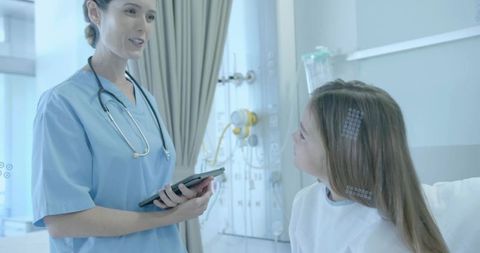 Pediatric nurse consulting with child patient using tablet in modern hospital room