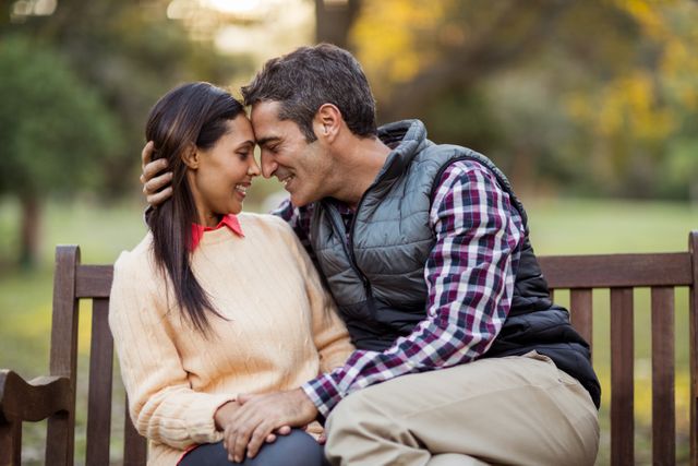 Couple embracing on park bench, enjoying a romantic moment outdoors. Perfect for use in relationship blogs, dating websites, and advertisements promoting love and togetherness.