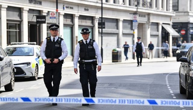 Two police officers walking patrolling city street with cordon tape and patrol car
