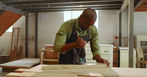 Skilled Carpenter Marking Wood Plank in Workshop