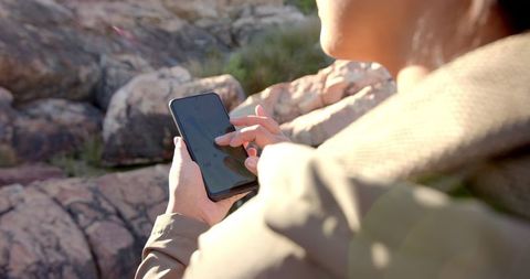 Woman Using Smartphone for Navigation on Rocky Mountain Path