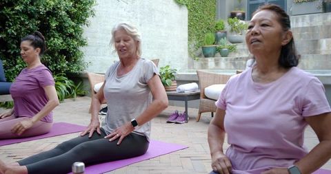 Mature women practicing gentle yoga on patio for wellness and mindful breathing