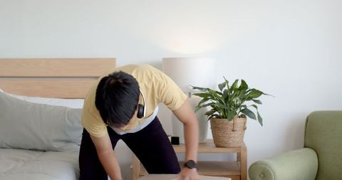Man packing cardboard box indoors with headphones