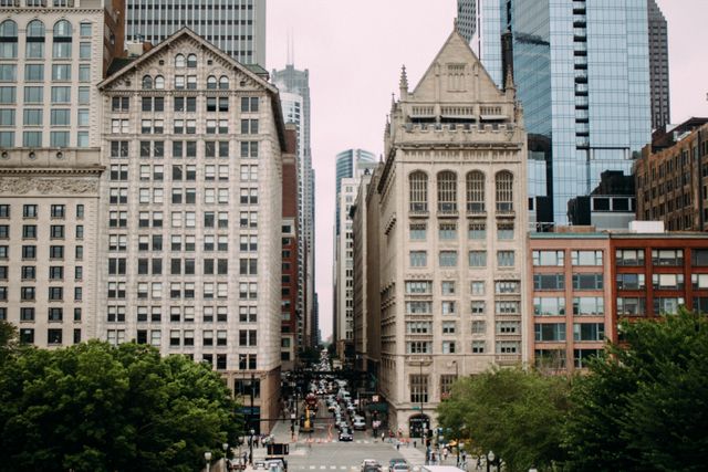 This image shows a busy downtown street flanked by historic buildings. The architecture features older, detailed facades juxtaposed with modern skyscrapers. Suitable for use in articles or projects about urban development, city architecture, commercial districts, and historical preservation efforts.