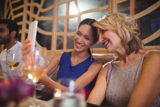 Two beautiful women taking selfie on mobile phone in restaurant