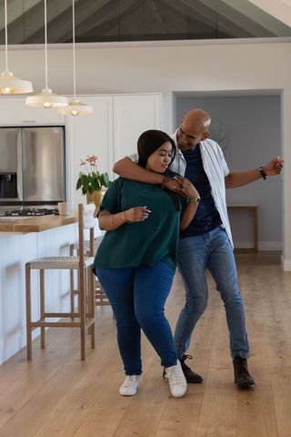 African american couple embracing and dancing in modern open-plan kitchen