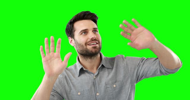 Bearded man in casual shirt presenting with hands up in front of green screen background. Ideal for presentations, advertisements, and video editing projects that require background removal or replacements.