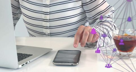 Professional reaching for smartphone on minimalist desk with laptop and networking overlay
