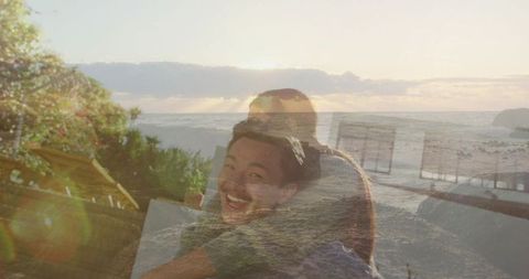 Sunset double exposure of couple embracing on coastal deck with smiling asian man