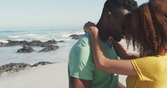 Couple sharing a romantic moment on a beach with the ocean in the background. Ideal for use in promotional materials related to travel, romance, relationships, and leisure activities. Great for websites, brochures, or advertisements focused on vacation getaways or love and affection themes.