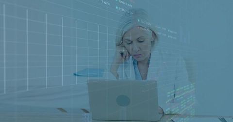 Senior Woman Analyzing Financial Data on Laptop with Futuristic Overlay