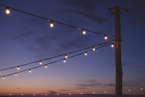 Twinkling string lights glowing at dusk over serene ocean horizon