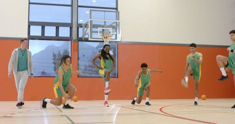 Diverse Basketball Team Exercising with Coach on Court