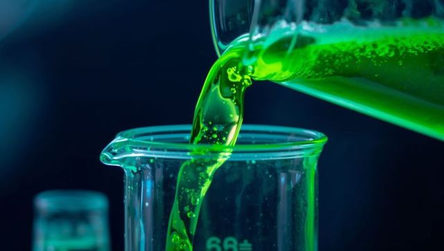 Neon green liquid pouring into beaker closeup fluorescent chemistry lab concept