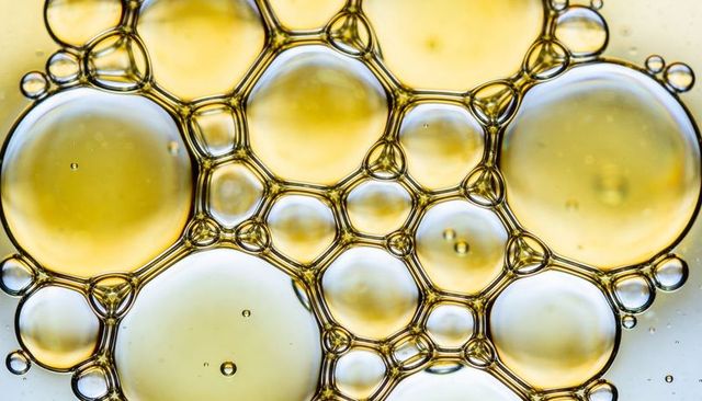 Amber oil bubbles forming honeycomb tessellation macro close-up with backlit gloss