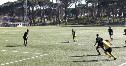 Soccer Match with Players in Black and Yellow Uniforms on Field