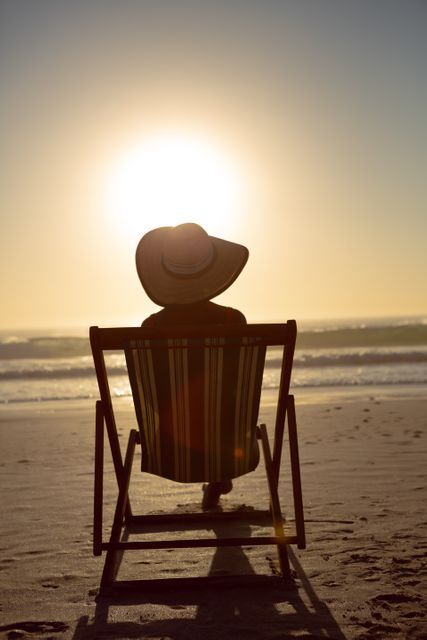 Rear view of thoughtful woman relaxing in a beach chair on the beach