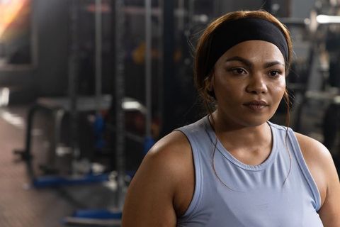 African american woman training in gym wearing headband and tank top, focused strength