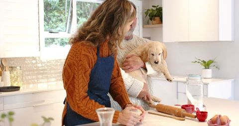 Cozy Sunlit Kitchen Baking: Couple Kneading Dough While Partner Cradling Puppy
