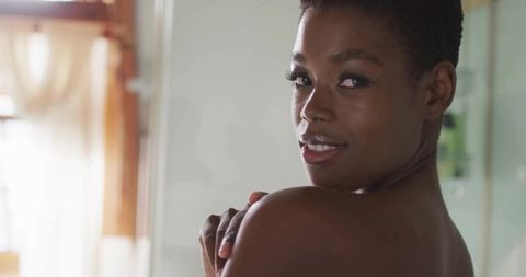 Woman with bare shoulders glancing in tranquil bathroom setting