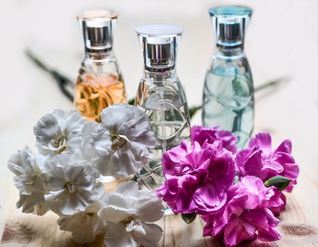 Fragrance bottles surrounded by colorful flowers on wooden surface - Download Free Stock Photos Pikwizard.com